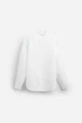Camisa color beige claro, de corte relaxed fit, confeccionada en tejido de lino y algodón. Tiene cuello mao, manga larga con puños abotonados y cierre frontal con botones.