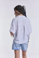 Camisa blanca de mangas cortas con dobladillo, cuello clásico, cierre frontal con botones y dos bolsillos frontales con solapa.