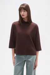 Polera holgada de poliéster color verde militar, con cuello alto tipo tortuga y mangas tres cuartos.