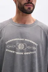 Remera gris de manga corta ranglan con estampa frontal que dice "Underground Movement Street-Made Identity".
