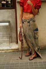 Falda larga de denim con efecto lavado y múltiples bolsillos cargo. Presenta una abertura lateral y cierre frontal con botón y cremallera.