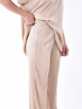 Pantalón de vestir color beige claro, de corte palazzo y tejido plisado.