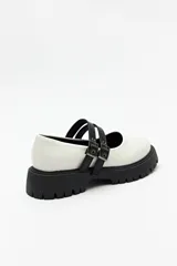 Guillerminas blancas de cuero sintético con suela track negra y doble tira ajustable con hebillas metálicas.