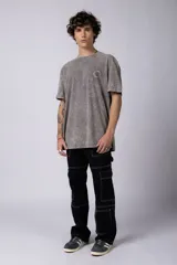 Remera de hombre color gris oscuro con efecto gastado (snow wash), corte semi-oversize y un pequeño estampado circular en el pecho que simula una obra de arte.