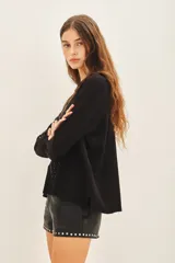 Sweater negro de moldería holgada, liviano y de caída relajada. Con aplicación de tachas termofijadas que expanden desde el hombro hacia el bajo ruedo de forma radial.