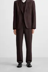 Pantalón de vestir color marrón oscuro, de corte recto, con bolsillos laterales y traseros de doble vivo. Cierre frontal con cremallera y botón.