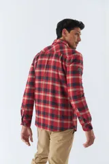 Sobrecamisa de algodón para hombre con interior de corderito, estampado a cuadros en tonos negro, blanco y azul. Tiene cierre de botones, bolsillos tipo cartera y logo en goma. El modelo usa talle M.