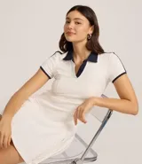 Vestido corto blanco de tejido rib, estilo skater, con cuello polo contrastante azul marino y escote en V. Presenta ribetes contrastantes en el borde del cuello, mangas cortas y en los bordes de las sisas.