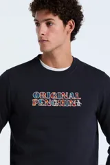 Buzo de tejido de punto color azul marino oscuro, con cuello redondo y puños y ruedo acanalados. Presenta un estampado frontal con el texto "ORIGINAL PENGUIN" en letras con patrón de cuadros multicolor.