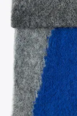 Bufanda rectangular de tejido de punto con diseño geométrico en tonos grises y azul.