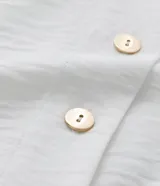 Blusa blanca de crepé con escote en V, abotonada en el frente y mangas cortas abullonadas.