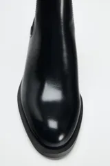 Botín Chelsea negro de charol con caña de tejido elástico acanalado y tacón ancho.