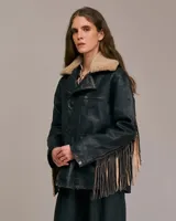 Chaqueta de cuero negra con cuello de borrego color crema, cierre de botones y flecos de cuero en las mangas.