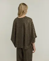 Blusa negra con estampado geométrico dorado, escote en V y mangas 3/4 amplias.