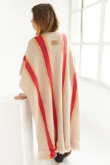 Ruana artesanal color beige con rayas horizontales rojas y amarillas, y flecos en el borde inferior.