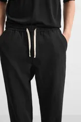 Pantalón negro de corte recto con cintura elástica ajustable con cordón, bolsillos laterales y traseros.