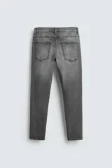 Pantalón de jean azul oscuro con efecto lavado y roturas en las rodillas, de corte ajustado al cuerpo desde la cintura hasta el tobillo.