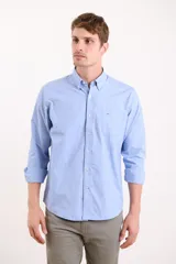 Camisa celeste con cuello abotonado, manga larga con puños abotonados y bolsillo en el pecho.