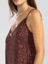 Vestido largo hasta el tobillo de viscosa y poliamida, con estampado de rayas verticales rosas y flores rojas. Tiene breteles finos, escote en V profundo y detalle de flor Polonio en cobre.