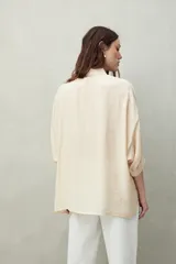 Camisa celeste de calce relajado con cuello clásico, mangas tres cuartos amplias y botones nacarados.