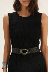 Vestido midi negro de lino, sin mangas, con escote redondo y falda fruncida. Incluye cinturón de cuero trenzado con hebilla metálica.