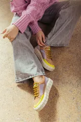 Zapatillas deportivas de cuero color beige con detalles en lila y amarillo.