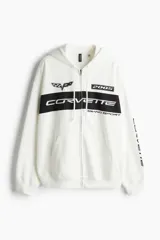 Campera con capucha blanca con cierre frontal y bolsillos tipo canguro. Estampado frontal con logo de Corvette, el año 2005 y la leyenda "Grand Sport". Estampado en la manga con la palabra "Corvette".