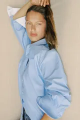 Camisa celeste de corte clásico, cuello solapa, escote en pico y manga larga.