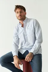 Camisa celeste a rayas rojas de hombre, manga larga, con bolsillo y logo bordado.