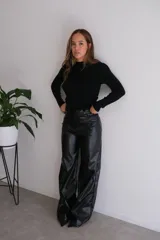 Pantalón negro de cuero sintético, corte palazzo y tiro alto.