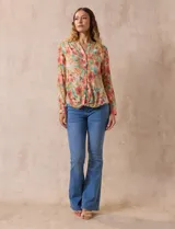 Blusa de gasa estampada a rayas verticales en tonos celeste, lila, naranja y marrón. Tiene cuello a la base con escote en V y botones. Delantera con bolsillo aplicado. Largo de manga regulable con presilla y botón. Terminación anudada opcional.