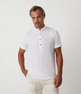 Camisa blanca de lino con cuello mao, manga corta y abotonadura parcial.