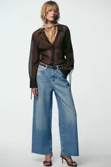 Pantalón de jean celeste de tiro alto, corte wide leg cropped, con cinco bolsillos y cinturón marrón con tachas.