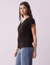 Remera blanca de lino, marca Zac & Rachel, con escote en V, abertura con botones y frunce en la parte delantera.