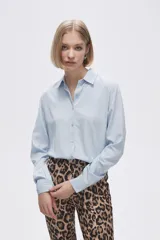 Camisa blanca de manga larga con cuello clásico y cierre frontal con botones. Corte recto y holgado.