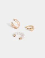 Set de tres cuffs dorados con diferentes diseños: uno con perlas, otro con forma de cadena y otro con un corazón.