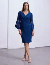 Vestido de noche RM Richards en seda fría color azul. Presenta escote en V cruzado, detalle de broche con brillos en el lateral y mangas amplias con apliques de microtul.