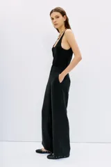 Pantalón palazzo negro de tiro alto, confeccionado en cupro y viscosa. Cuenta con bolsillos diagonales laterales, bolsillos ojal falsos en la espalda y cierre lateral invisible.