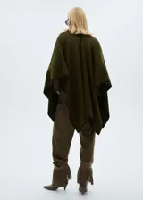Poncho verde militar con ribete negro en contraste, cuello alto y diseño holgado. Incluye cinturón negro con hebilla dorada.
