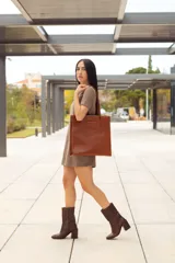 Bolso tote de cuero color marrón, con costuras a contratono y logo grabado en el frente.