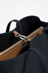 Bolso shopper horizontal Bimba y Lola, modelo Chihuahua, color negro, con doble asa de tejido, piezas de piel y logo metálico. Tiene cierre de mosquetón y bolsillo interior con cremallera.