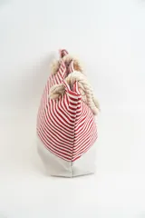 Bolso tipo tote con rayas horizontales rojas y blancas en la parte superior y base color beige. Asas de soga gruesa.