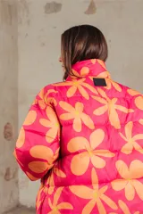 Campera puffer estampada con flores color naranja sobre fondo fucsia, de corte corto y cuello alto.