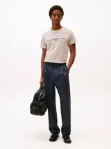 Remera de manga corta color gris claro con logo bordado de Tommy Hilfiger en el pecho. El logo combina letras azul marino y rojas, con la bandera blanca. Corte clásico y cuello redondo.