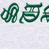 Canguro gris con capucha y bolsillo delantero, con logo Supreme en tipografía gótica verde.