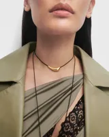 Gargantilla con cordón negro y dije dorado en forma de lágrima.