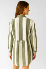 Vestido camisero midi de manga larga, con cuello camisero y cierre frontal de botones. Presenta un patrón de rayas verticales anchas en tonos azul claro y blanco.