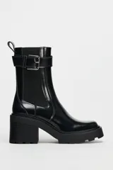 Botín negro estilo Chelsea con elástico lateral, hebilla decorativa y suela track con tacón bloque.