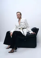 Pantalón negro de vestir, tiro medio, corte wide leg y aberturas laterales en el ruedo.