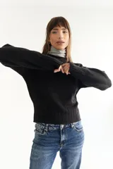 Sweater de punto negro con cuello alto y mangas largas.